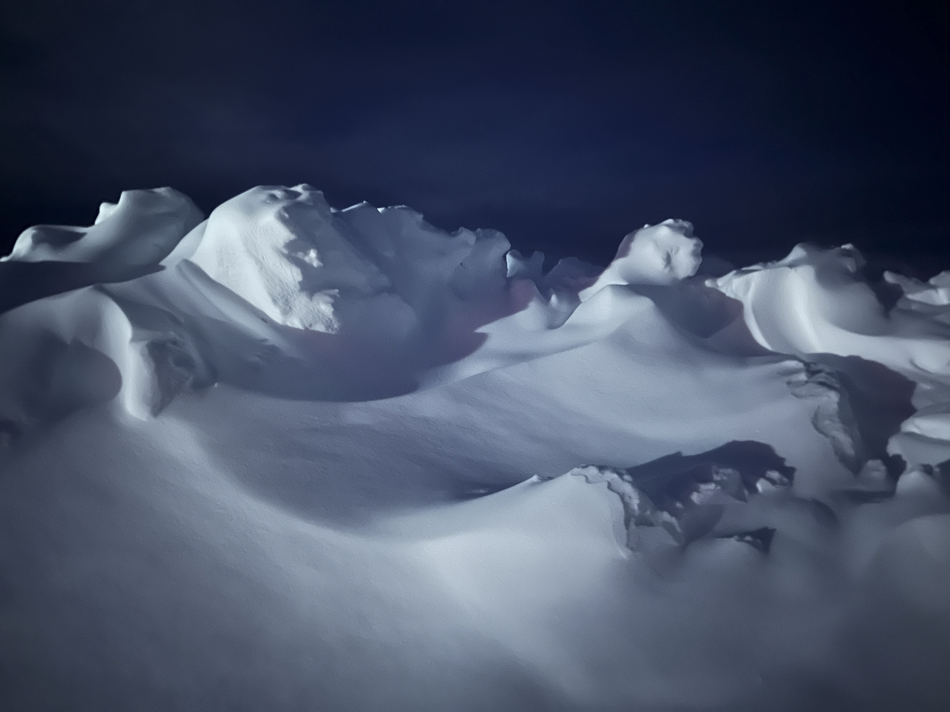 Wind-sculpted snow forms in winter blue light.