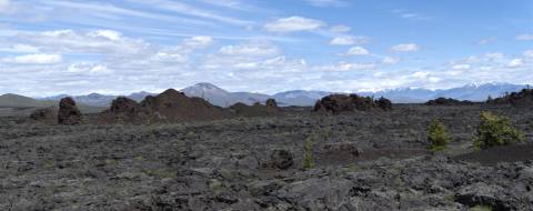 Panoramic view across a dark lava field at Craters of the Moon
