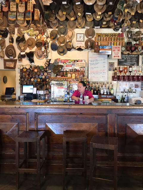 Wide view of an outback hotel bar lined with hats
