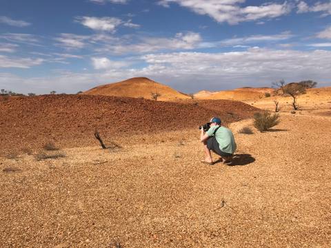 Field researcher photographing rounded desert hills