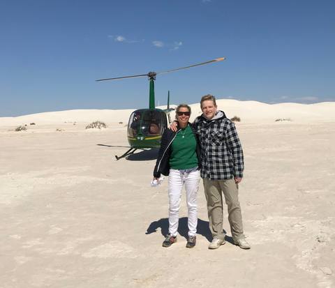 Lisa Wood and a colleague beside a helicopter on the White Sands dunes