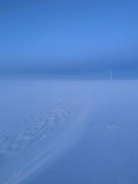 Faint road and snowfield fading into fog