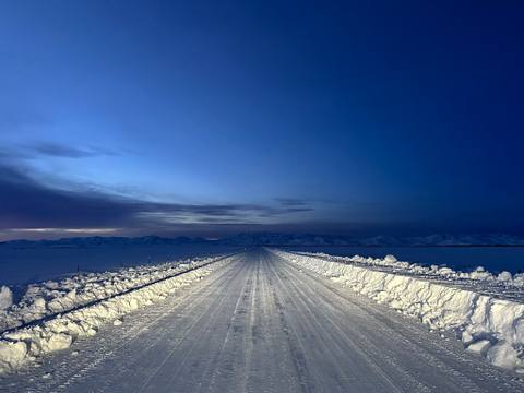 Snowbanked road under a deep blue storm sky