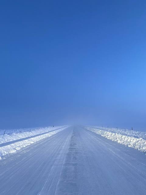Snow road and banks disappearing into blue fog