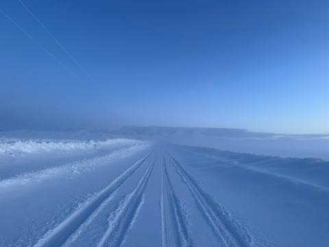 Twin tire tracks crossing the blue-white prairie