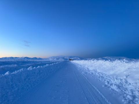 Snowbanked road at blue dawn with distant mountains
