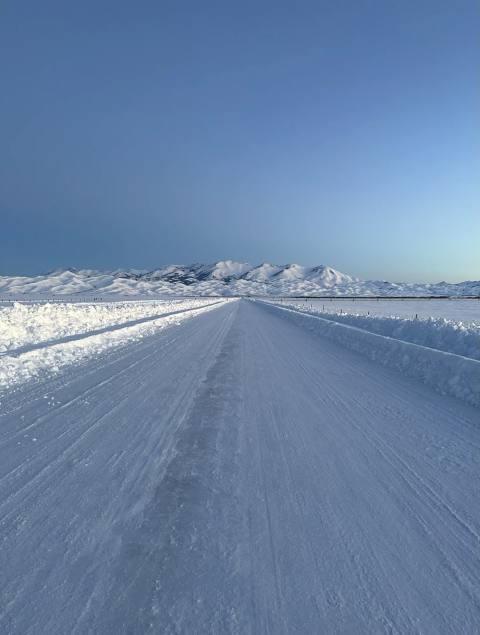Snow-covered Camas Prairie road leading toward distant mountains